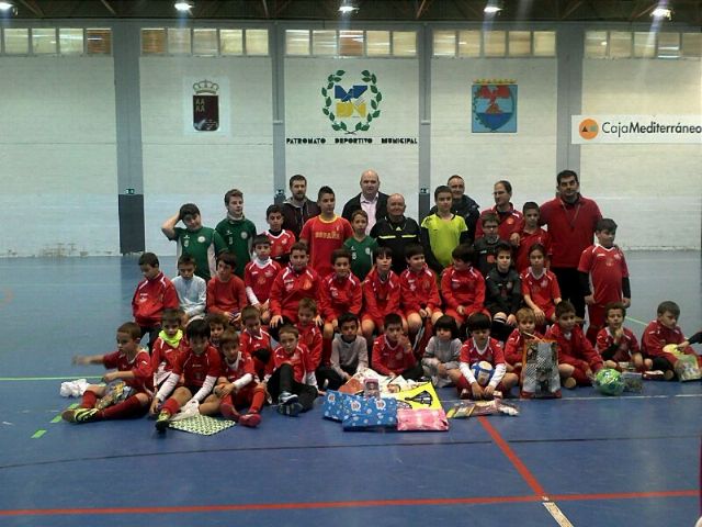 Alumnos participantes, monitores de la E.F.Sala Águilas y representantes de Cáritas junto a una pequeña muestra de los juguetes recogidos